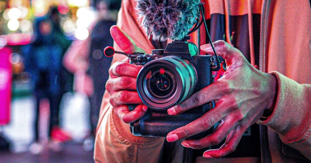 A videographer, camera in hand, capturing vibrant urban scenes filled with an array of colours and energy