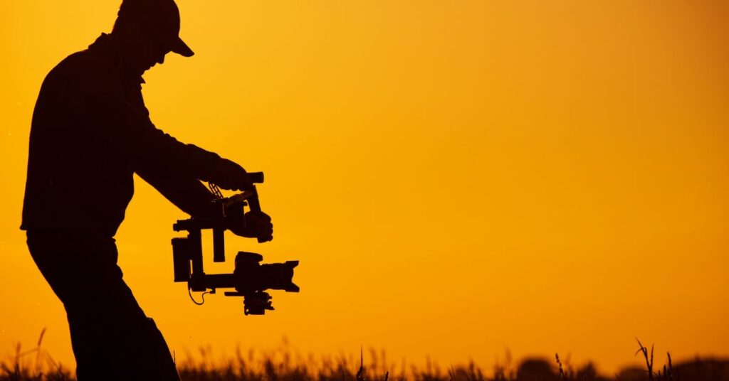 A videographer holding a stabilizer against the warm hues of sunset, capturing the essence of a tranquil Johannesburg evening.